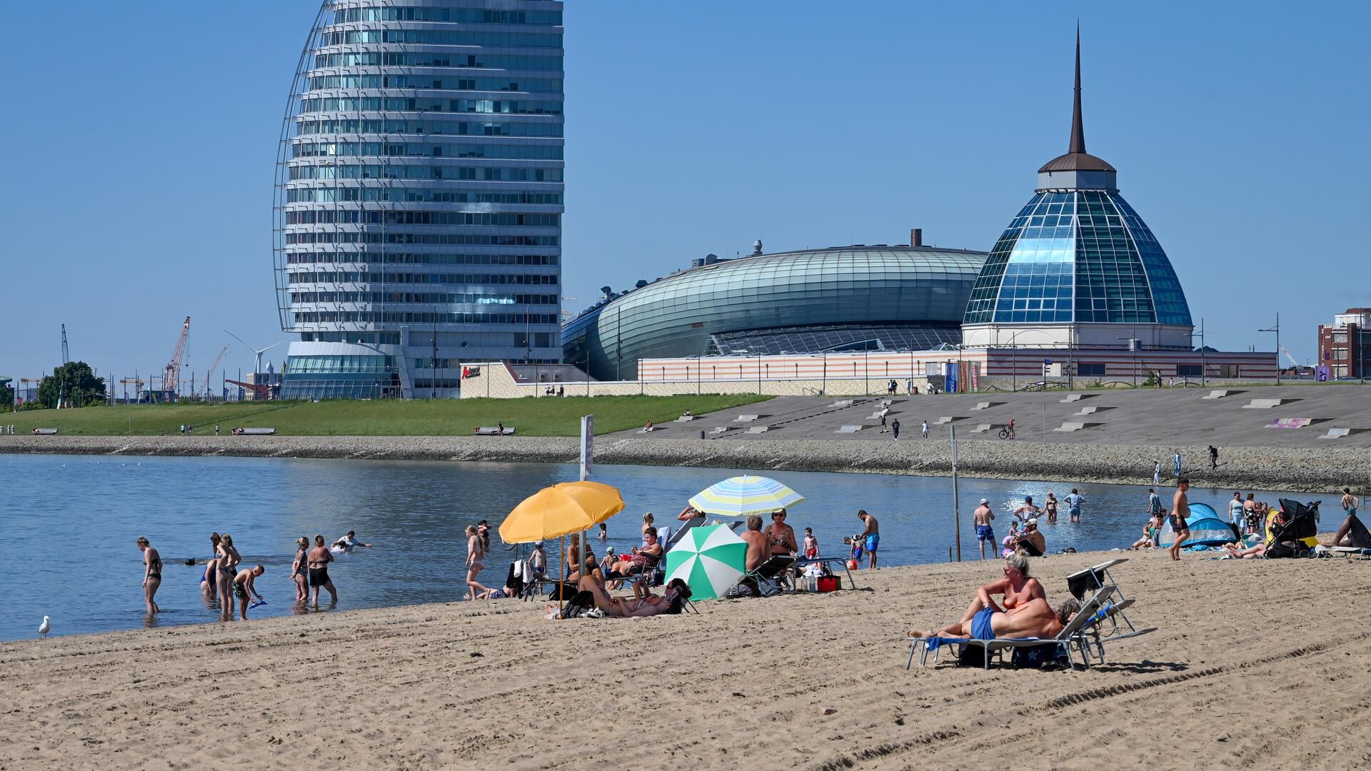 Strand in Bremerhaven mit Blick auf ein Hotel und das Klimahaus im Hintergrund. 