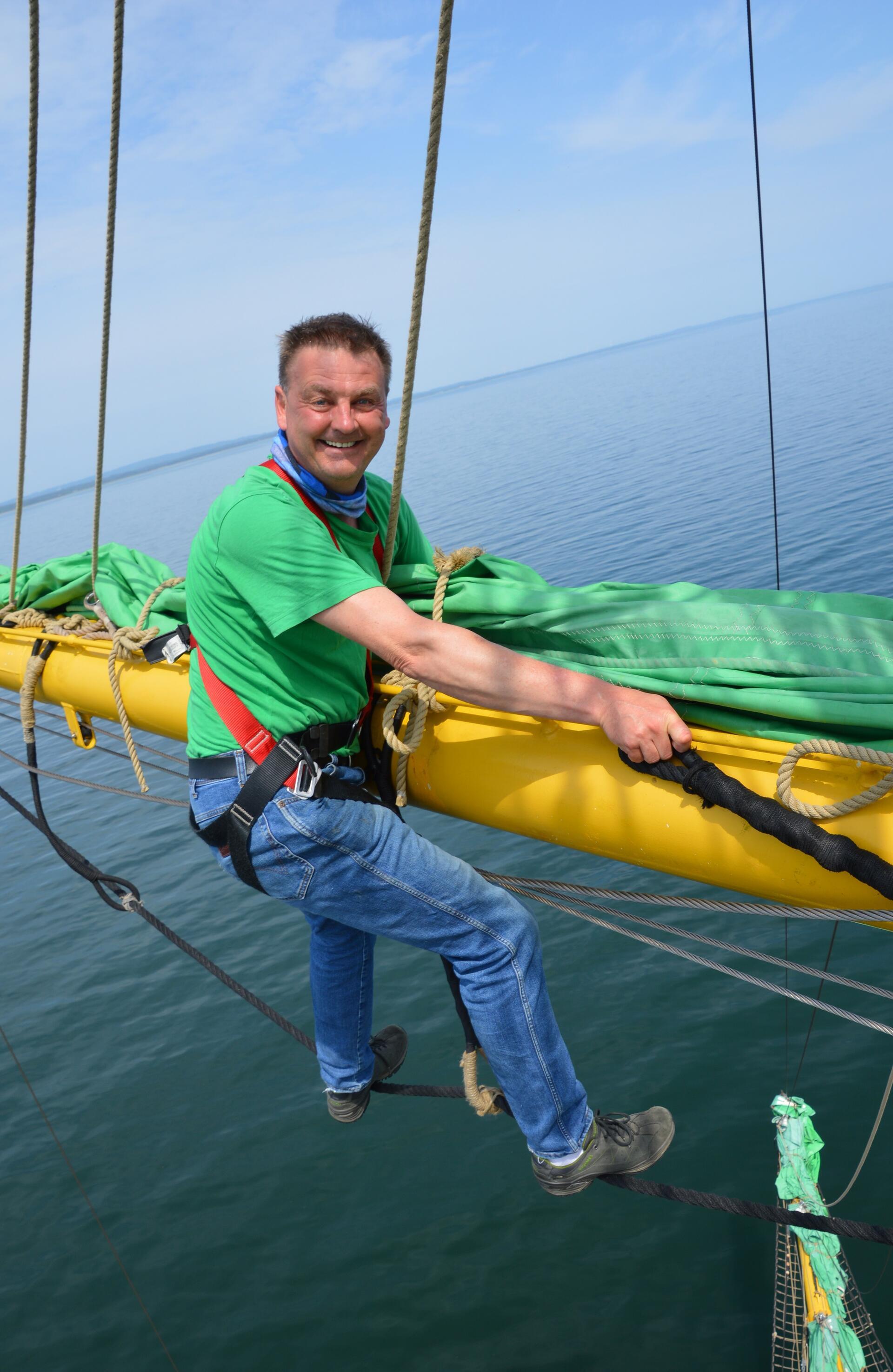 Ein Mann setzt auf einem großen Segelschiff die Segel