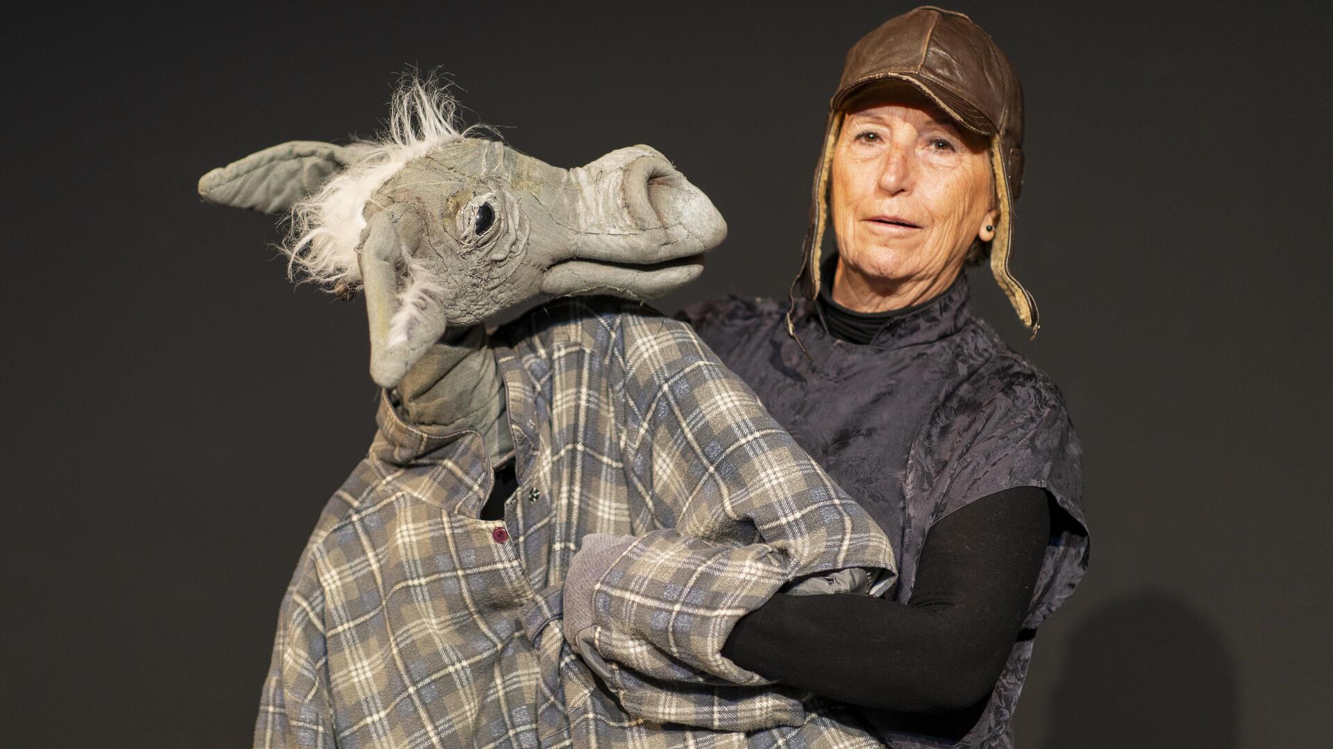 Eine ältere Frau, eine Puppenspielerin, mit einer lebensgroßen Eselsfigur.