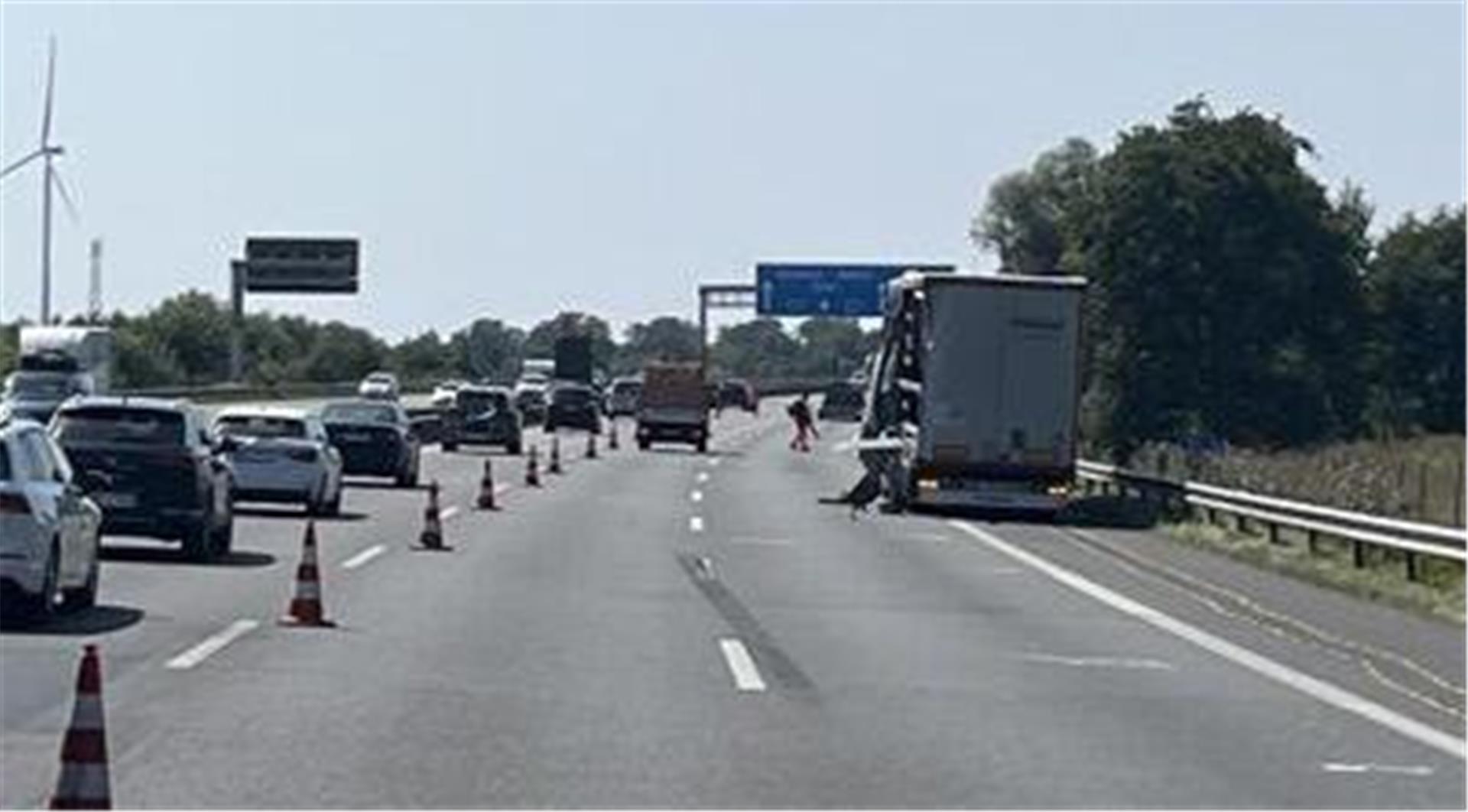 Auf einer dreispurigen Straße steht rechts ein LKW. Die linke Spur ist abgesperrt und dort fahren hintereinander mehrere Autos.