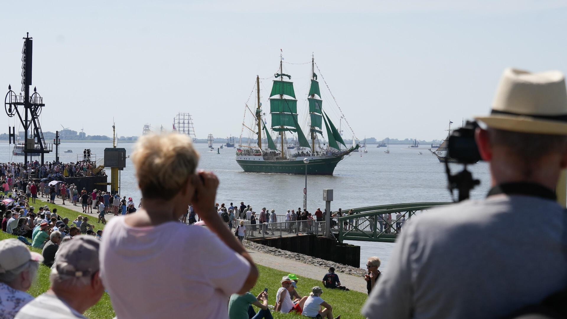 Menschen schauen sich in Bremerhaven die Einlaufparade der Sail 2025 an.