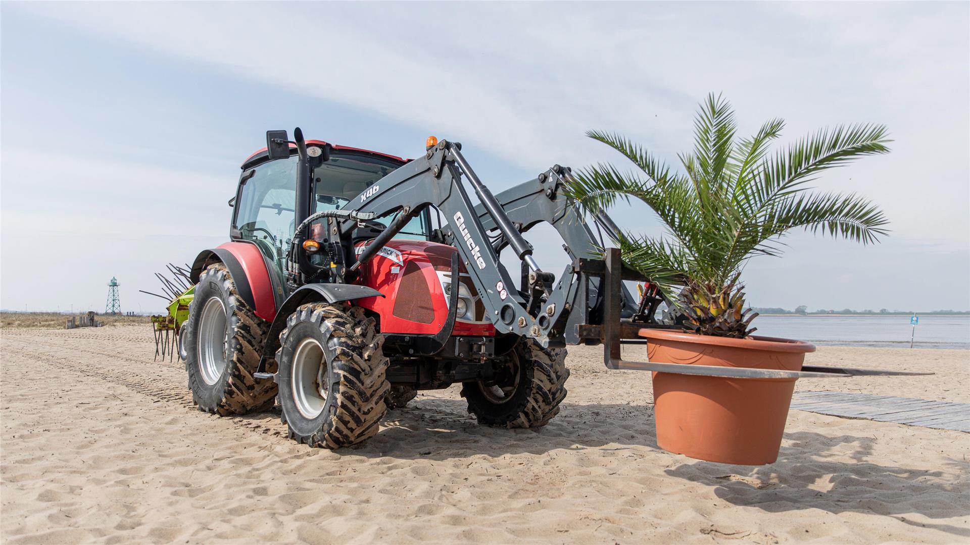 Ein Traktor mit Palme: Urlaubsfeeling per Gabelstapler – die Palmen ziehen an den Strand von Bremerhaven.