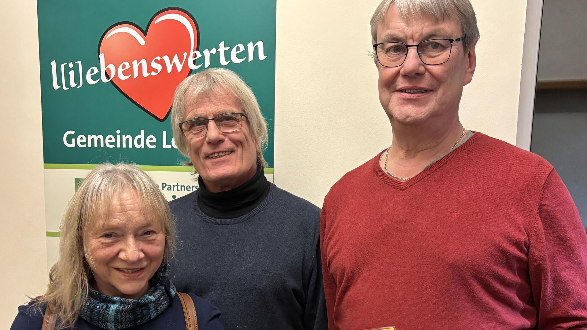 Drei Menschen lächeln in die Kamera. 
