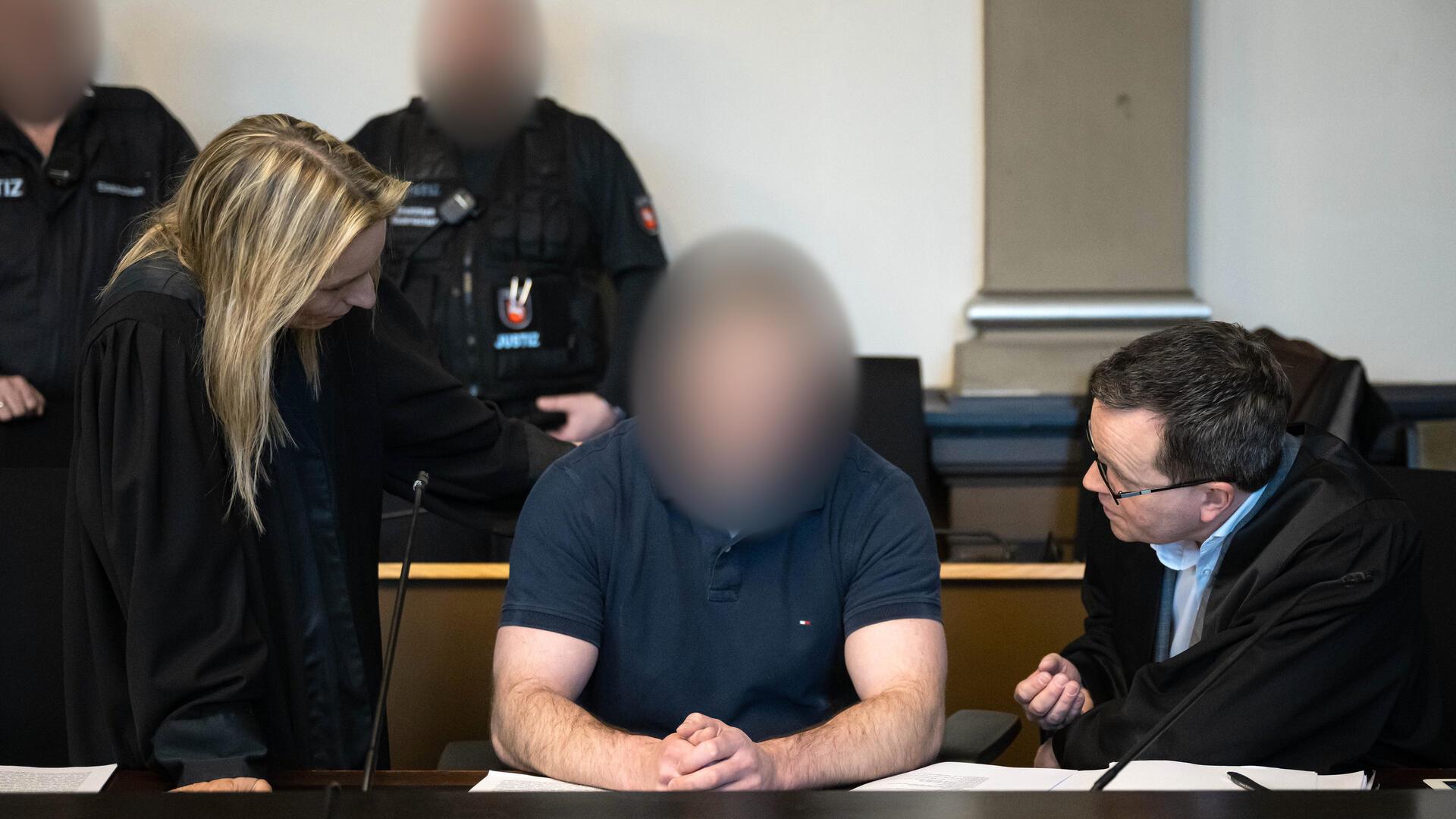 Ein Mann sitzt in einem Gerichtssaal. Sein Gesicht ist verpixelt.