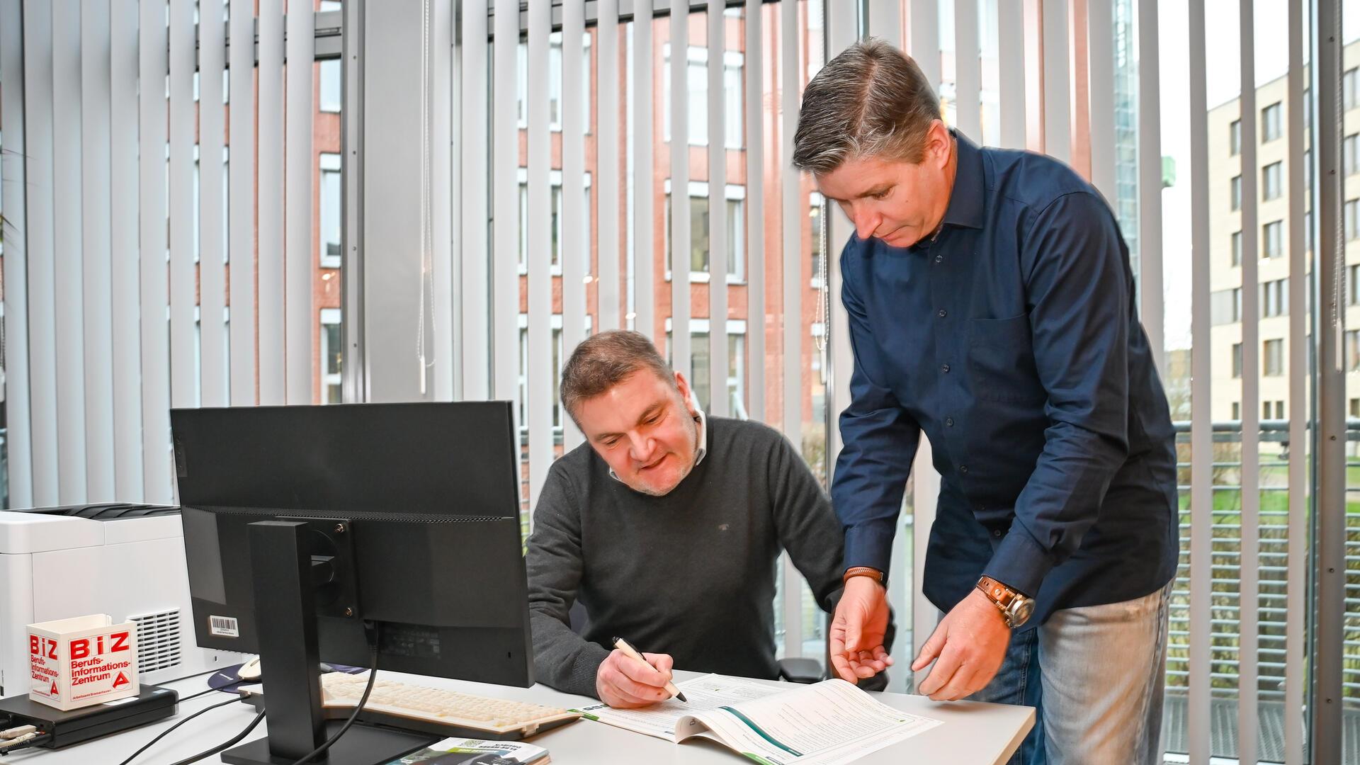 Welcher Job passt zu mir? Berufsberatung kann helfen, das Richtige zu finden Zwei Männer in der Bundesagentur für Arbeit stehen an einem Schreibtisch.