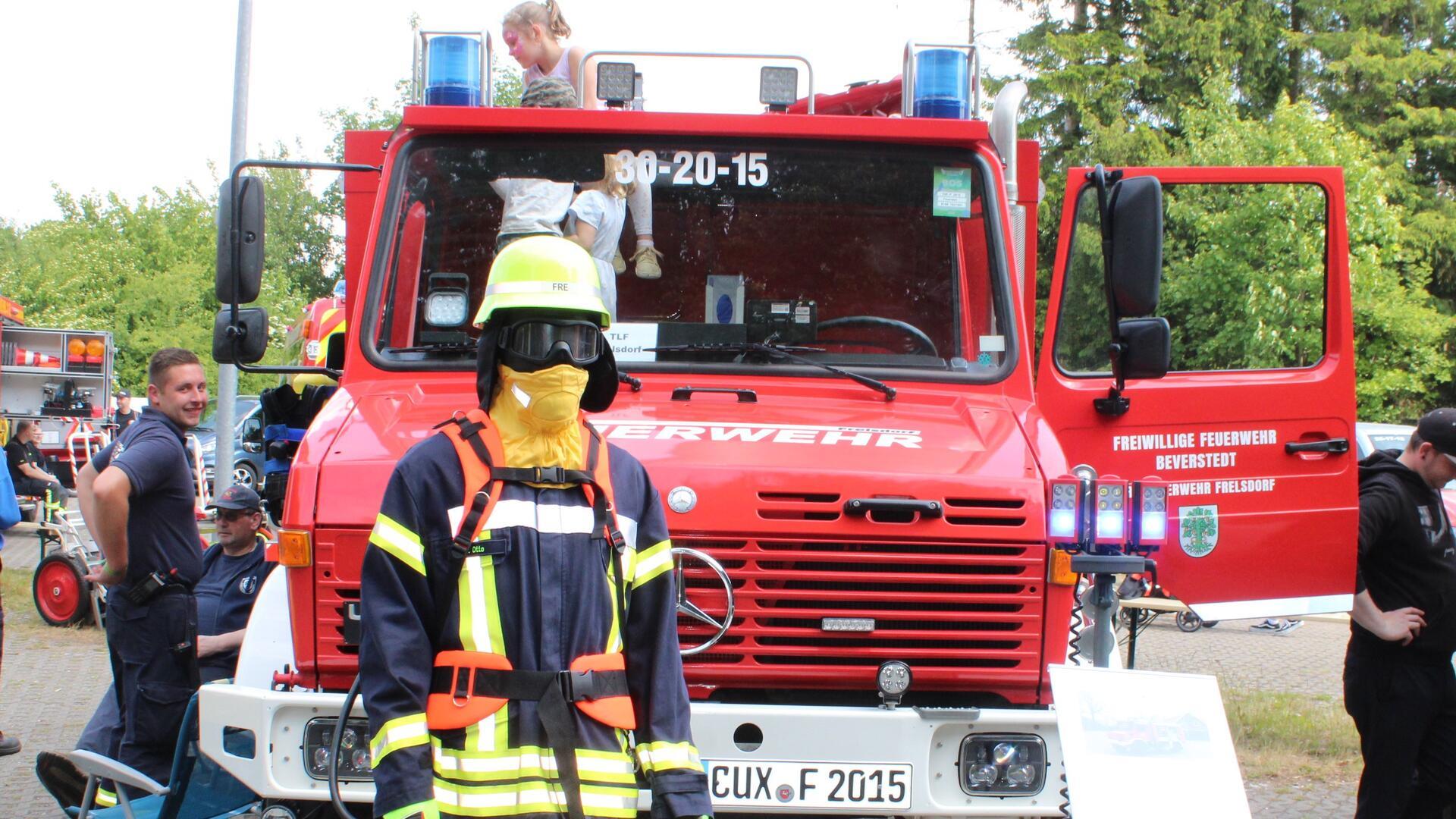 Kinder und Feuerwehrleute tummeln sich um ein Tanklöschfahrzeug. 