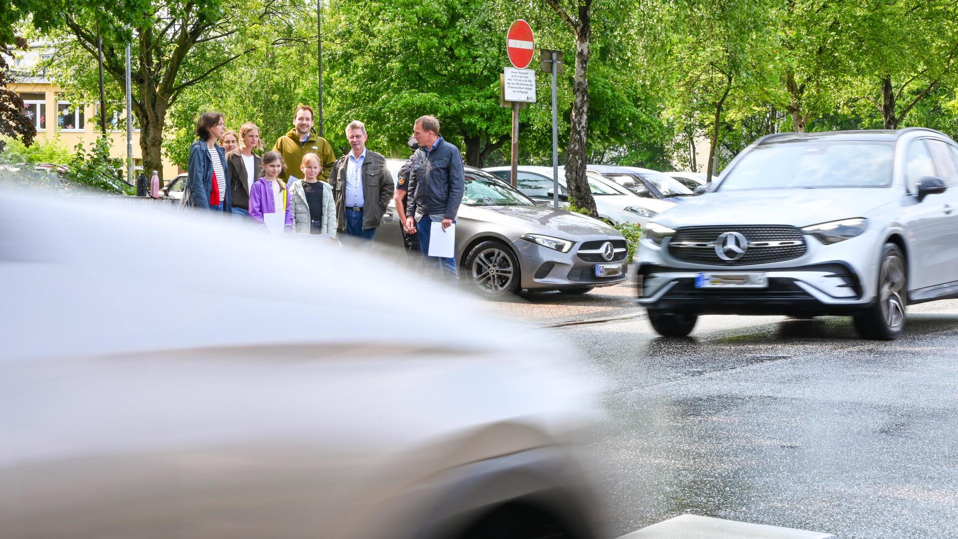 Schülersprecherinnen Hailey Kuhr (lila Jacke) und Louisa Wege (helle Jacke) zeigen den zuständigen Dezernenten der Stadt Bremerhaven die Verkehrssituation direkt am Zebrastreifen vor der Friedrich-Ebert-Grundschule am Mecklenburger Weg.