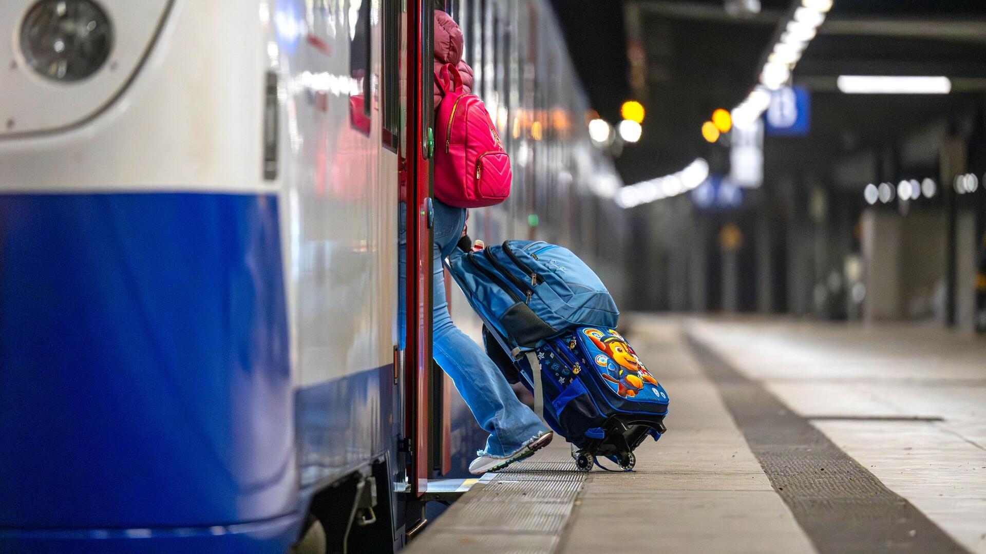 Eine Frau mit Koffern steigt in einen Regiozug der Nordwestbahn. 