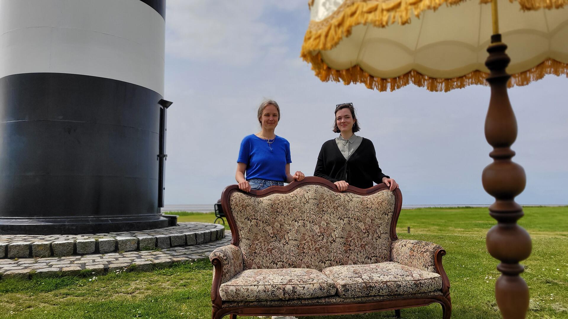 Von der Wremer Leuchtturmkulisse zum Nordholzer Bahnhof: Am 1. Juni „fliegt“ das Wurster Kultursofa mit seinen Initiatorinnen Ulla Puckhaber (links) und Saskia Stöwing von der Gemeinde Wurster Nordseeküste in den nördlichen Teil der Gemeinde.