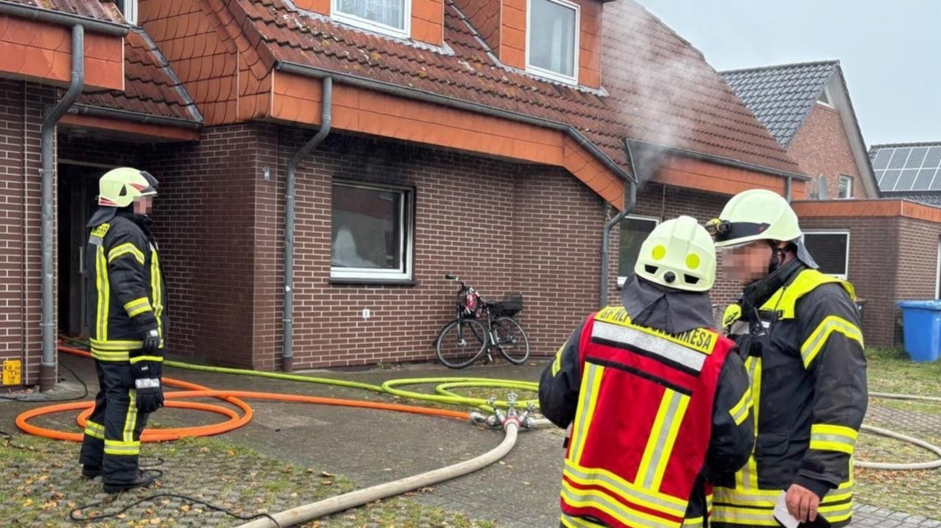 Eine Einsatzkraft der Feuerwehr steht neben einem Einsatzfahrzeug der Feuerwehr.