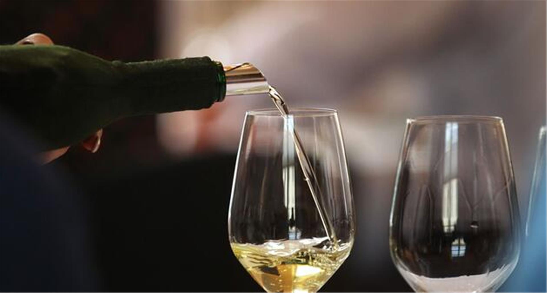 Ein Glas wird mit Weißwein gefüllt. 