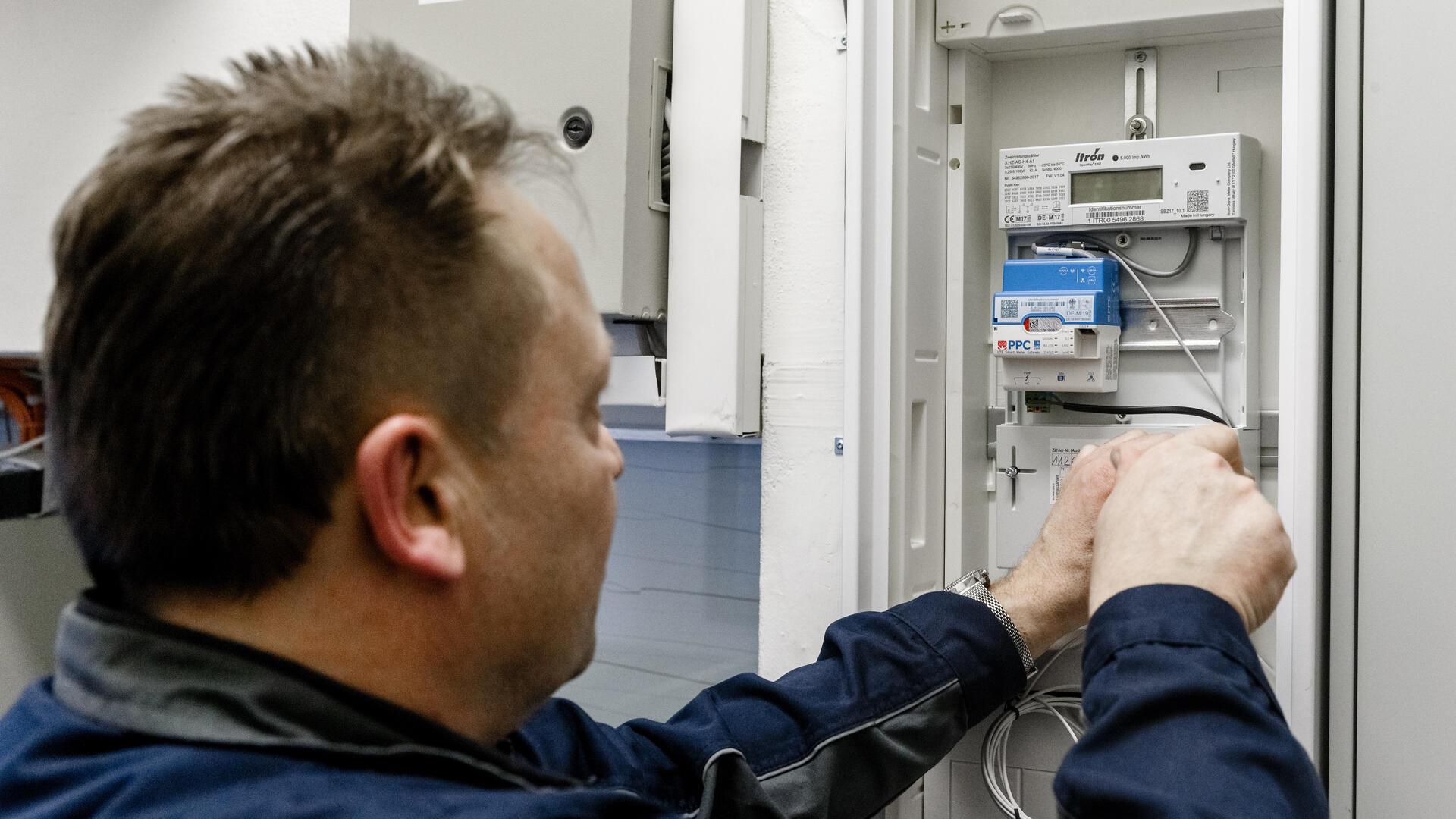 Ein Elektriker montiert einen digitalen Stromzähler mit einem Smart-Meter-Gateway zur Datenübertragung. 