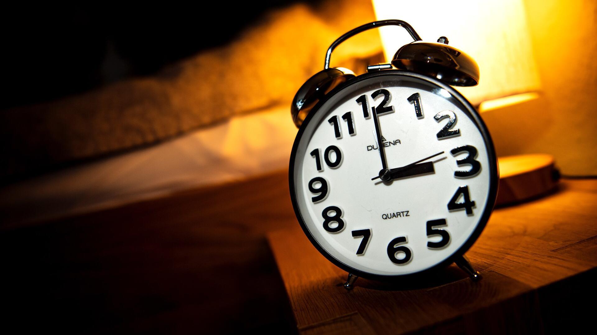  Eine Uhr steht neben einem Bett. 