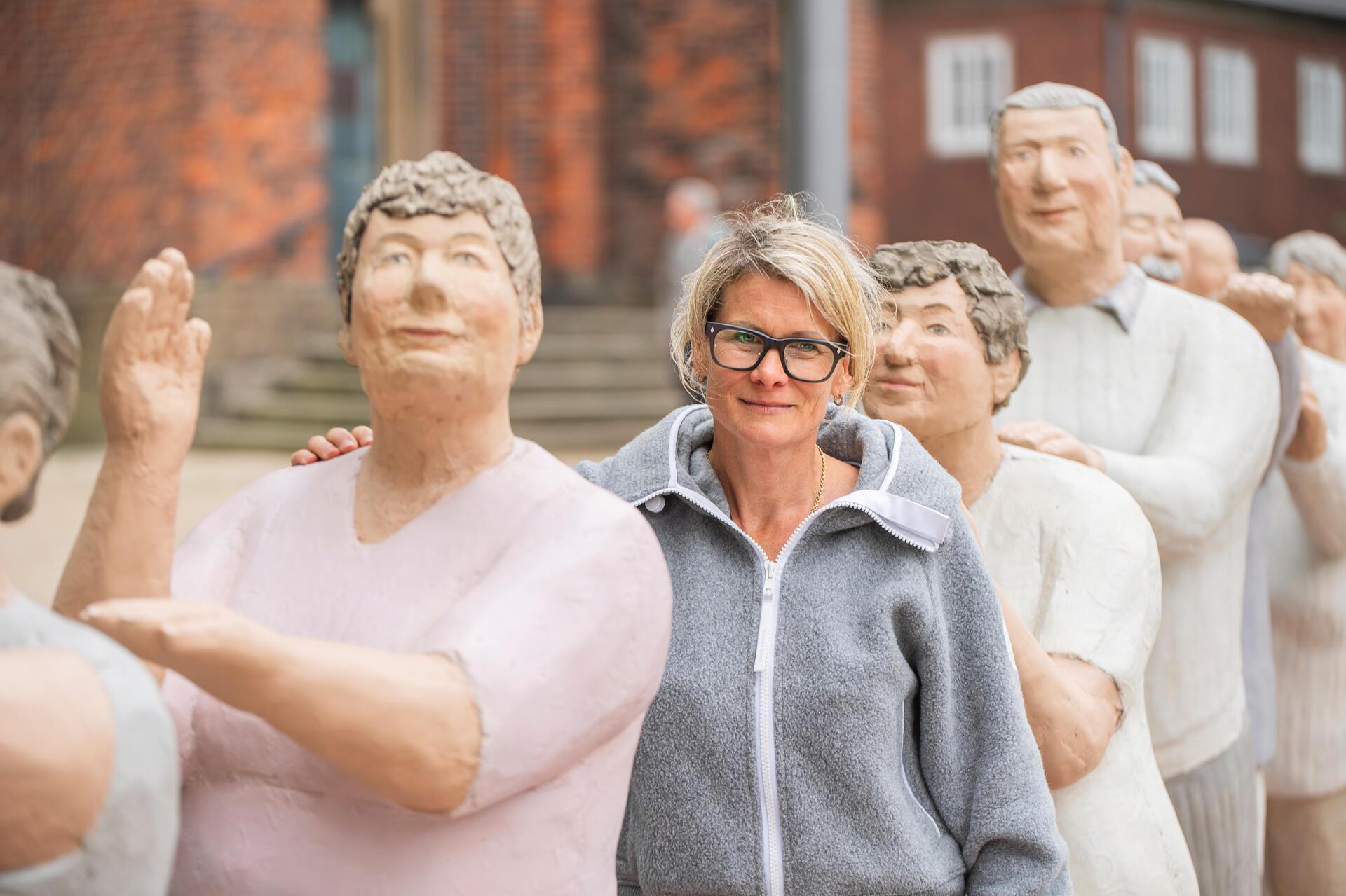 Frau zwischen lauter Beton-Figuren