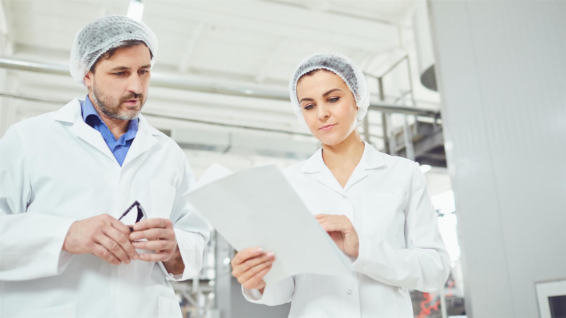 Zwei Kontrolleure blicken auf ein Blatt Papier.