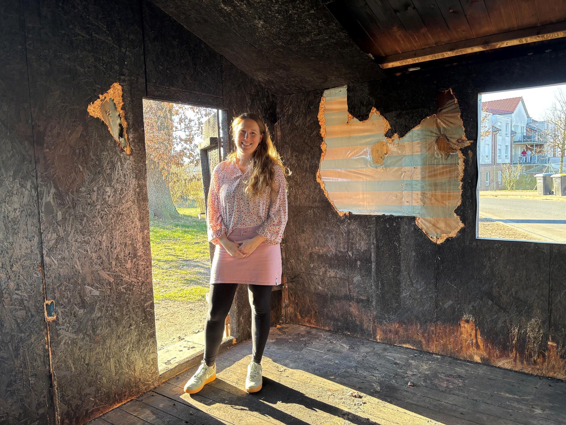 Eine Frau steht in einer Holzhütte. Seit einem Brand ist das Tarmstedter Tauschhaus eine Ruine.