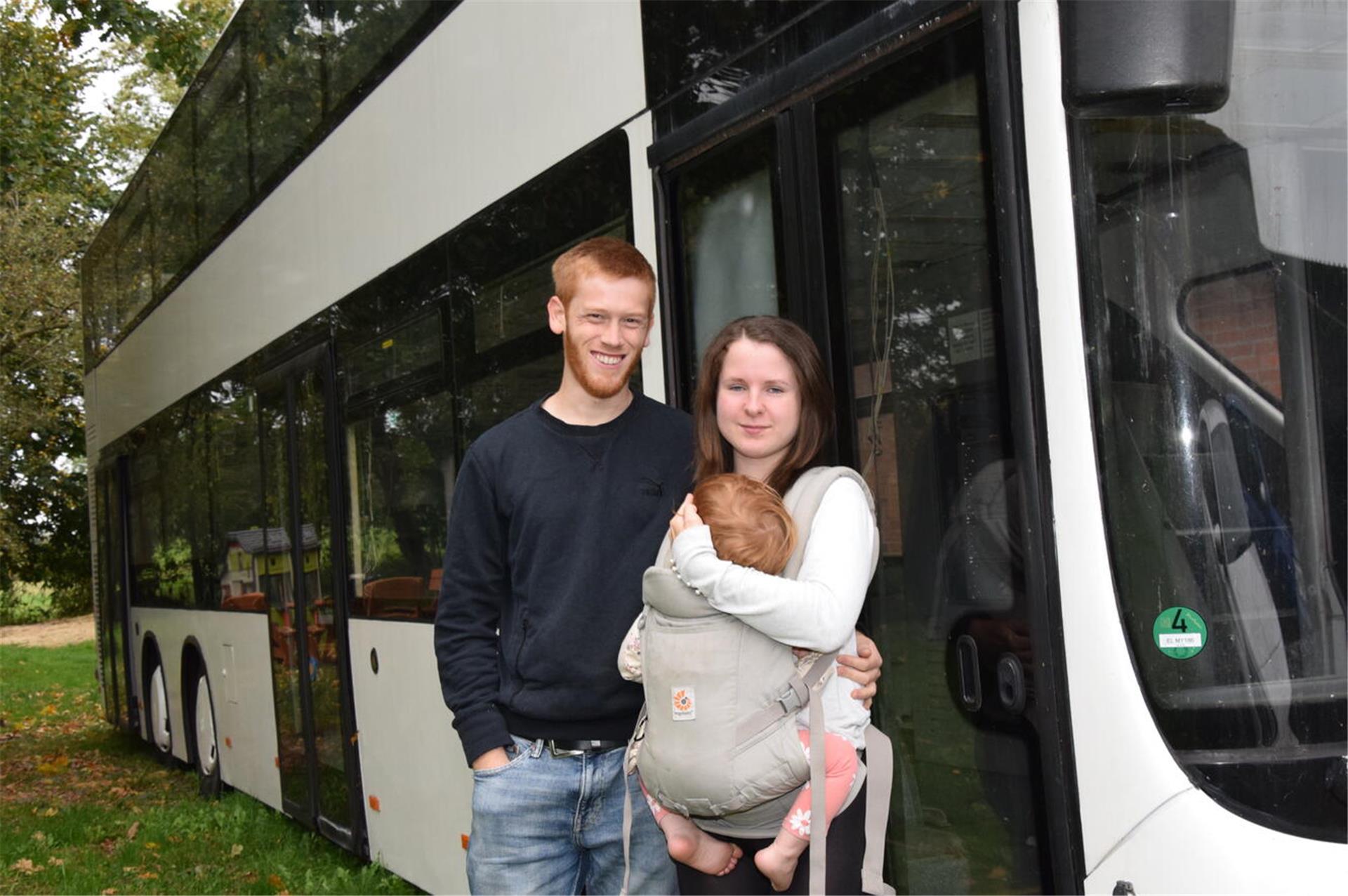 Drei Menschen vor einem Doppeldecker-Bus.