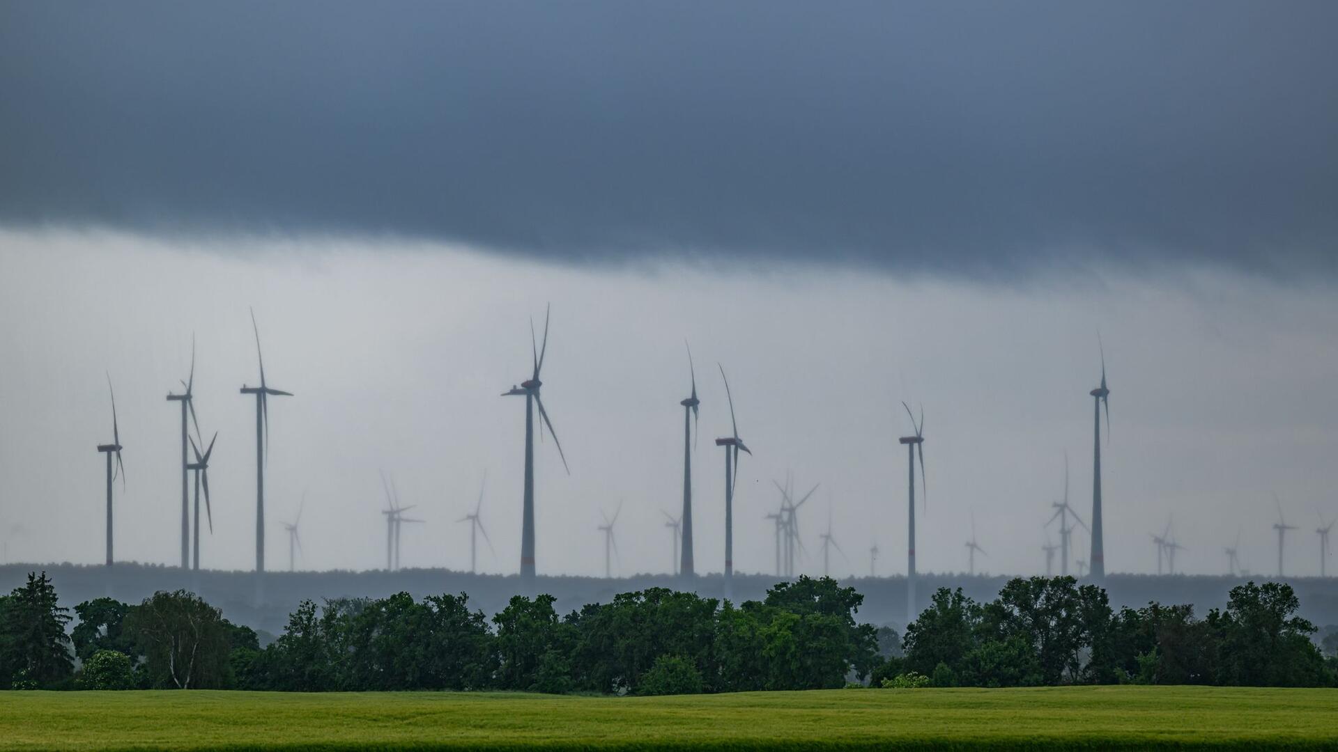  Dunkle Wolken und Regen ziehen über einen Windpark