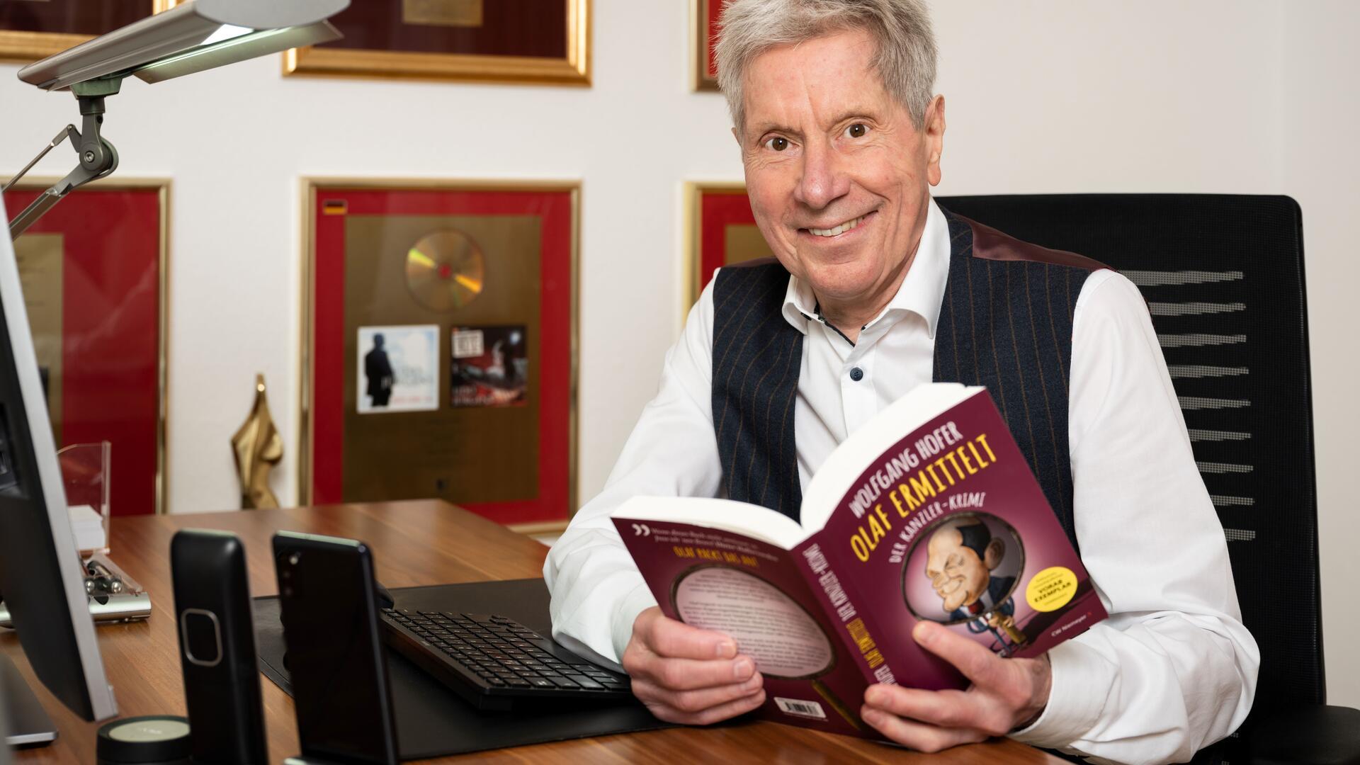 Ein älterer Mann hält ein Buch in der Hand. 