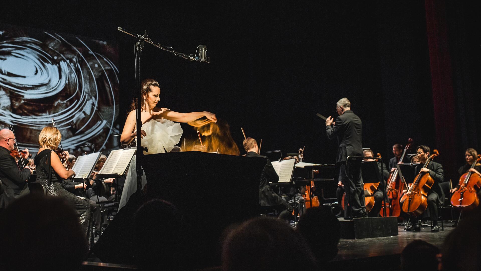 Wolken aus rotem Sahara-Sand zu spätromantischem Sommernachtstraum im Orchester: Die ukrainische Sand-Künstlerin Svetlana Telbukh und Gastdirigent Dietger Holm präsentierten mit dem Philharmonischen Orchester Bremerhaven ein fulminantes Neujahrskonzert am Stadttheater. 