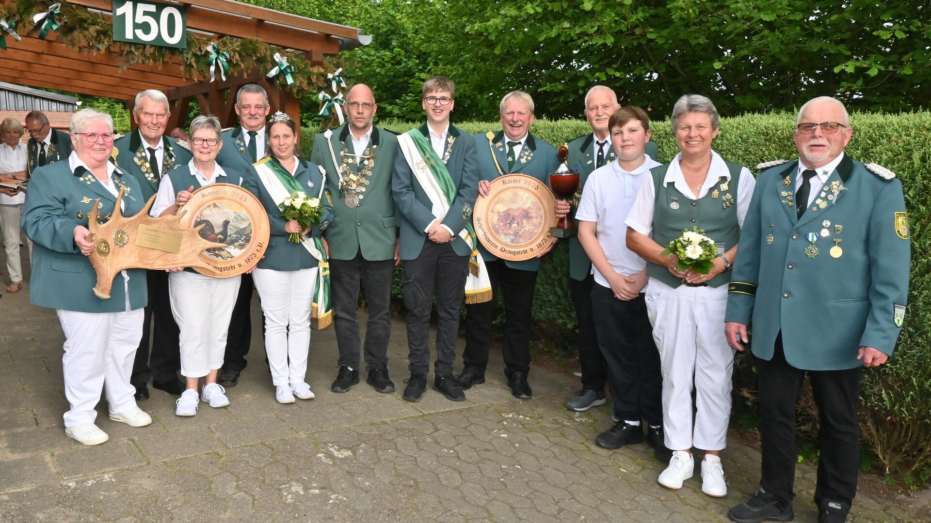 Gruppenfoto des Schützenvereins Drangstedt: Die neuen Majestäten und weitere Geehrte posieren in Uniform mit Schützenketten, Blumen und Ehrenscheiben.