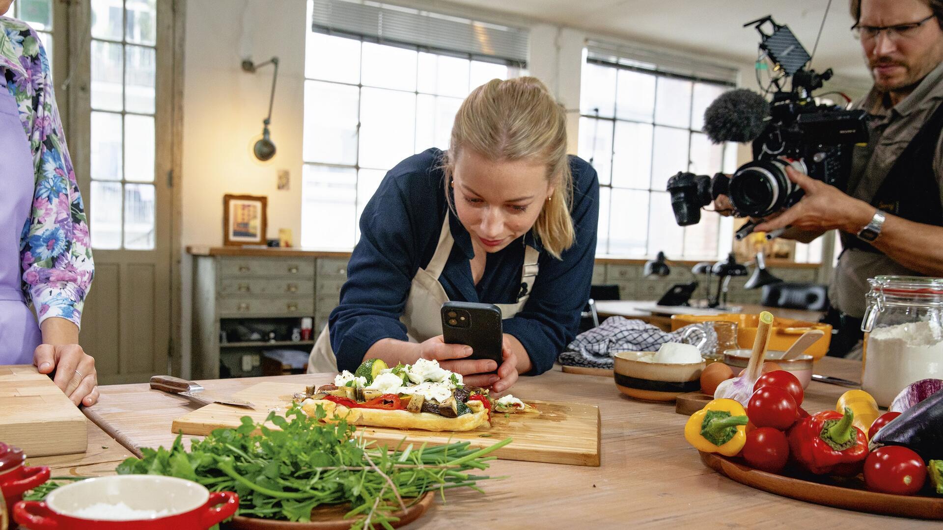 Zora Klipp aus Zeven macht mit dem Handy ein Foto von einem belegten Brot auf einem Tisch.