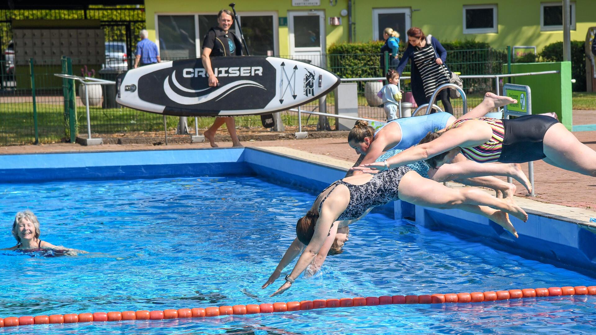 Frauen in Badeanzüge springen kopfüber in ein Schwimmbecken.